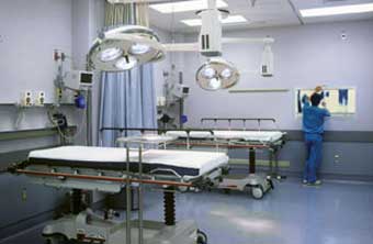 Two people in white scrubs and masks fixing machinery